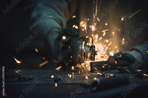 Obraz na płótnie Pipe cutting with a circular grinder on a table with pieces of metal. Sparks flying in the workshop. w salonie