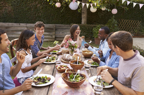 Friends Eating And Drinking Around Table At Outdoor Party
