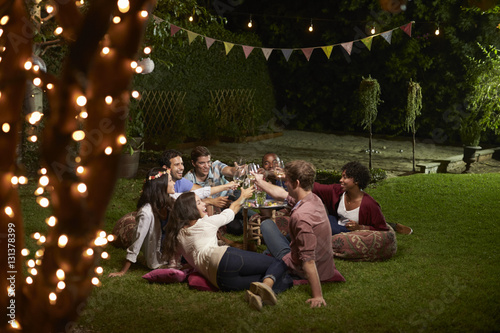 Group Of Friends Making A Toast At Evening Drinks In Garden