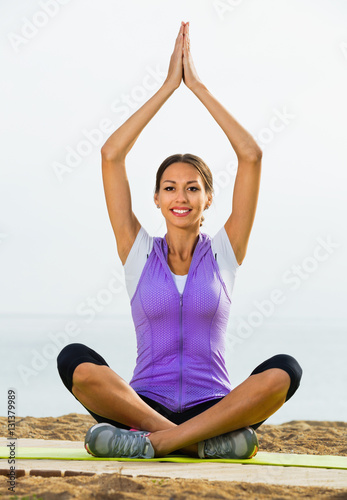 Woman doing youga training cross-legged on beach