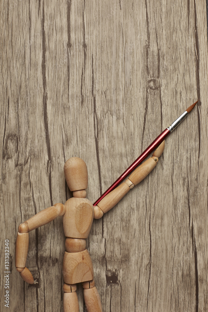 Wooden mannequin with paintbrush
