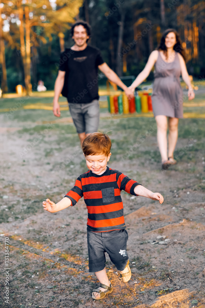 A little boy runs away from his parents in the summer in the park A little boy runs away from his parents in the summer in the park