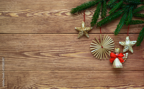 Christmas wooden background with branches of fir tree and straw decorations , empty space.