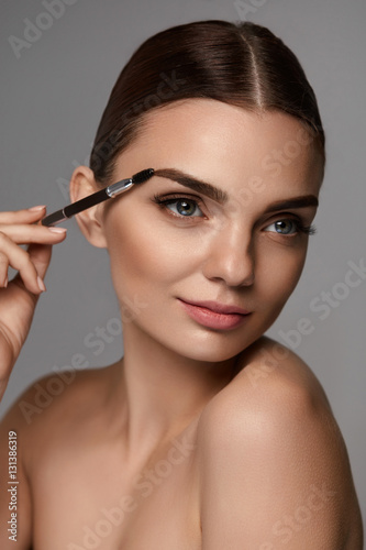 Beautiful Woman Brushing Eyebrows With Brow Tool photo