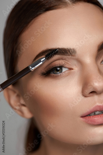 Beautiful Woman Brushing Eyebrows With Brush. Beauty photo