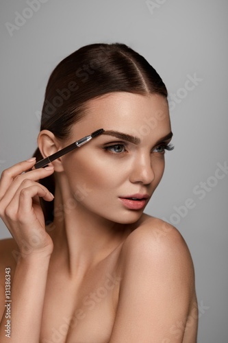 Beautiful Woman Brushing Eyebrows With Brow Tool photo