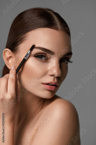Beautiful Woman Brushing Eyebrows With Brow Tool photo