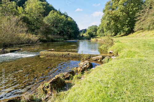 Photography River Lathkill, tumbles over a low weir on its way through Lathkill Dale, Derbyshire