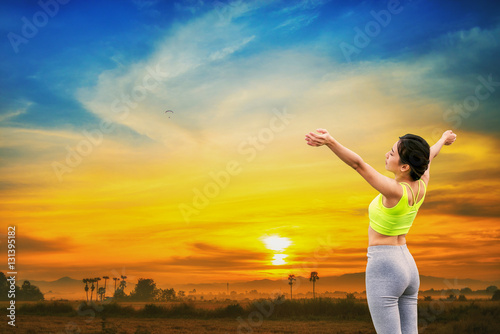 Sport girl standing with raised arms and enjoying a beautiful nature.