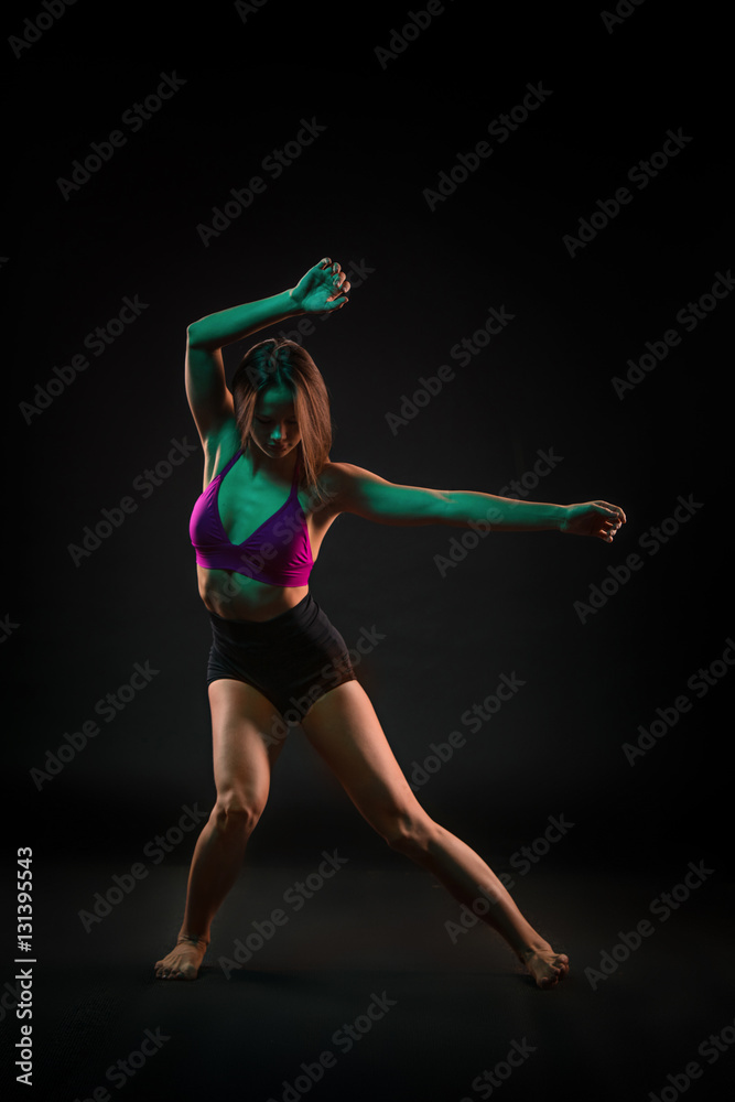 Young beautiful dancer in beige dress dancing on black background