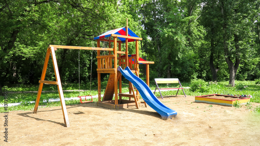 A children's playground, a slider located on the sand.