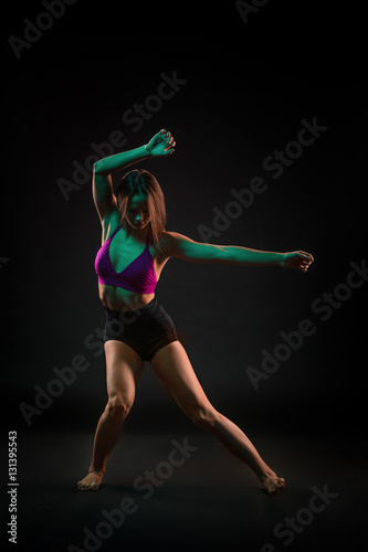 Young beautiful dancer in beige dress dancing on black background