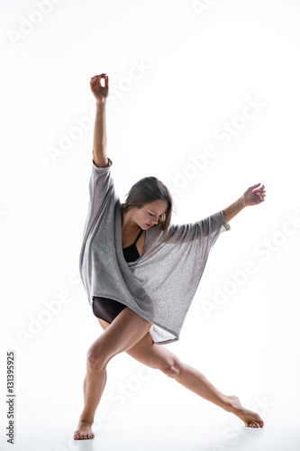 Young beautiful dancer in beige dress dancing on white background
