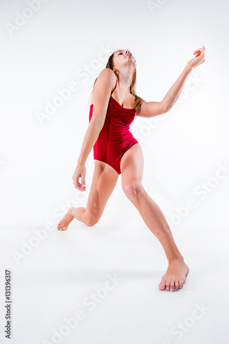 Young beautiful dancer in beige dress dancing on white background