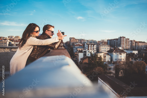 Couple taking pictures on the rooftop © kerkezz