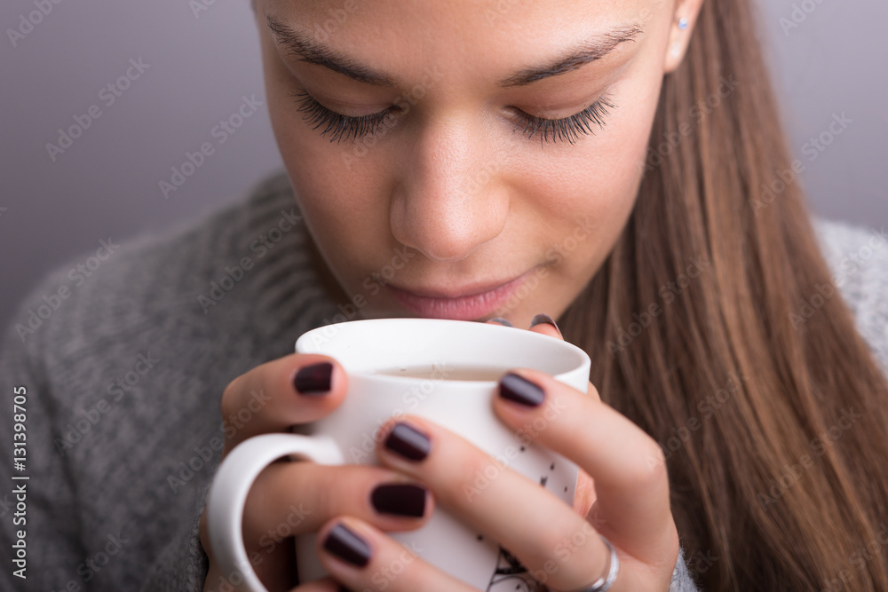 Young woman drink coffee or tea. isolated gray.
