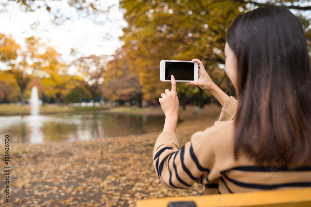 Woman taking photo at park in autumn season