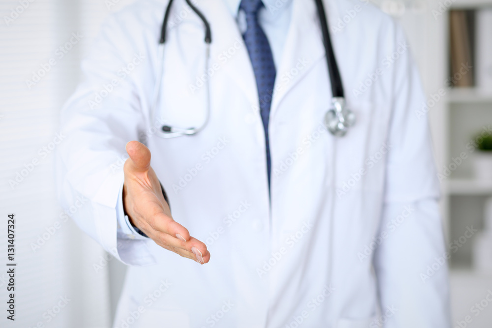 Male medicine doctor offering helping hand for handshake. Partnership and trust concept. Male medicine doctor offering helping hand for handshake. Partnership and trust concept.