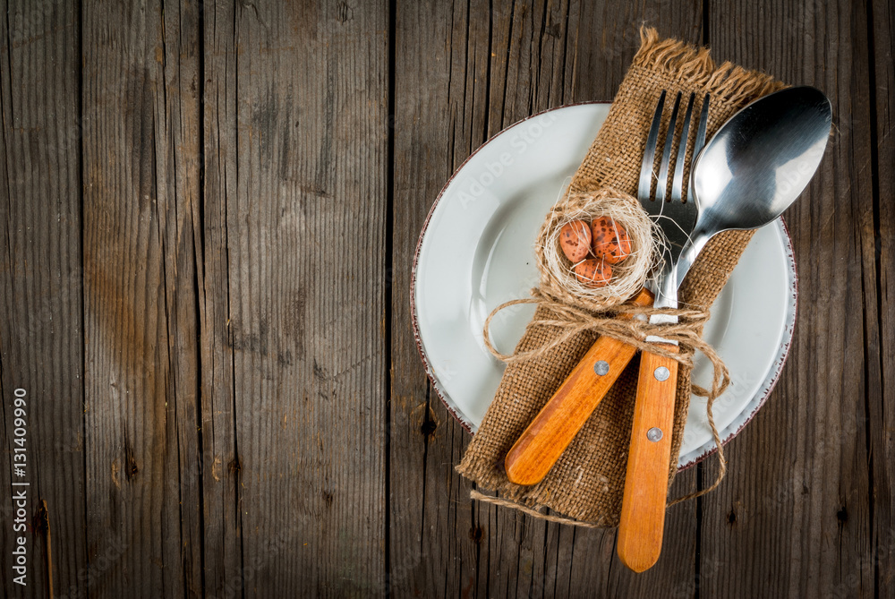 Spring Easter wooden table setting with plate, decorative nest with egg, flowers, cutlery and napkin. Copy space Spring Easter wooden table setting with plate, decorative nest with egg, flowers, cutlery and napkin. Copy space