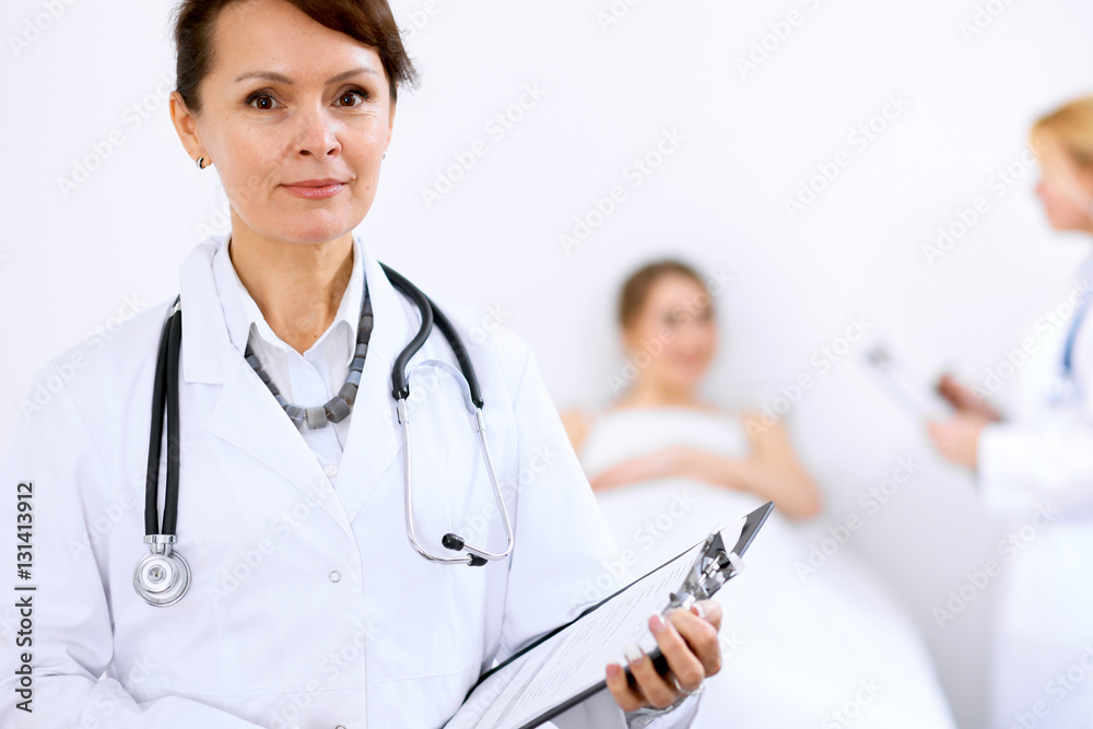 Female doctor smiling on the background with patient and his doctor Female doctor smiling on the background with patient and his doctor