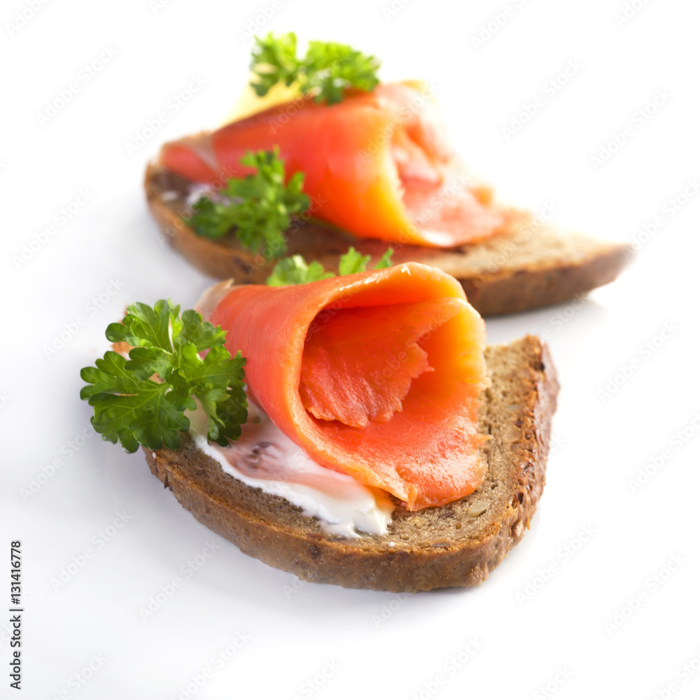 Two sandwiches with smoked salmon, sauce and parsley on a white background Two sandwiches with smoked salmon, sauce and parsley on a white background