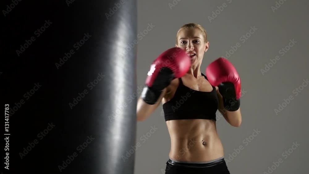 Kicking on the punching bag by a woman boxer Kicking on the punching bag by a woman boxer