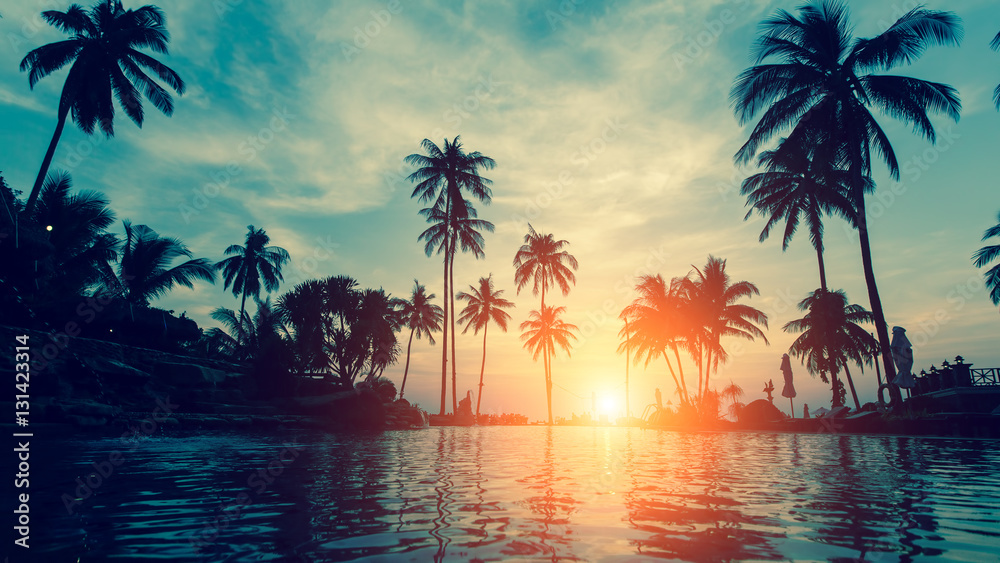 Obraz premium Piękna tropikalna plaża z palmami sylwetki o zmierzchu.