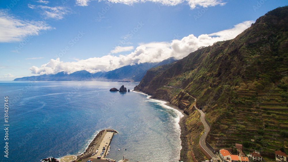 Obraz premium Coastal road with steep coast and beautiful blue ocean sky, Madeira, Portugal
