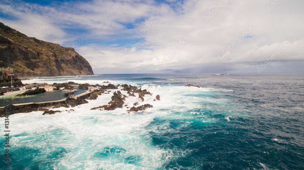 Naklejka premium Waves and rocks near city pools of Porto Moniz aerial view
