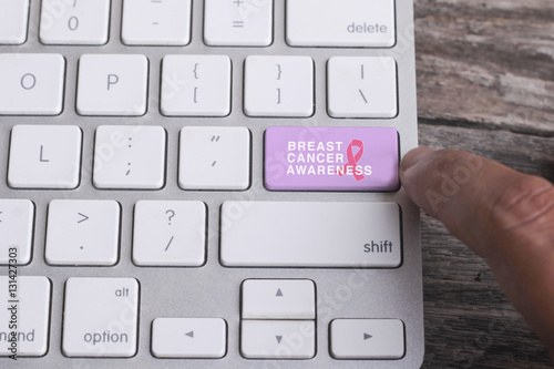 Close up of finger on keyboard button with BREAST CANCER AWARENESS