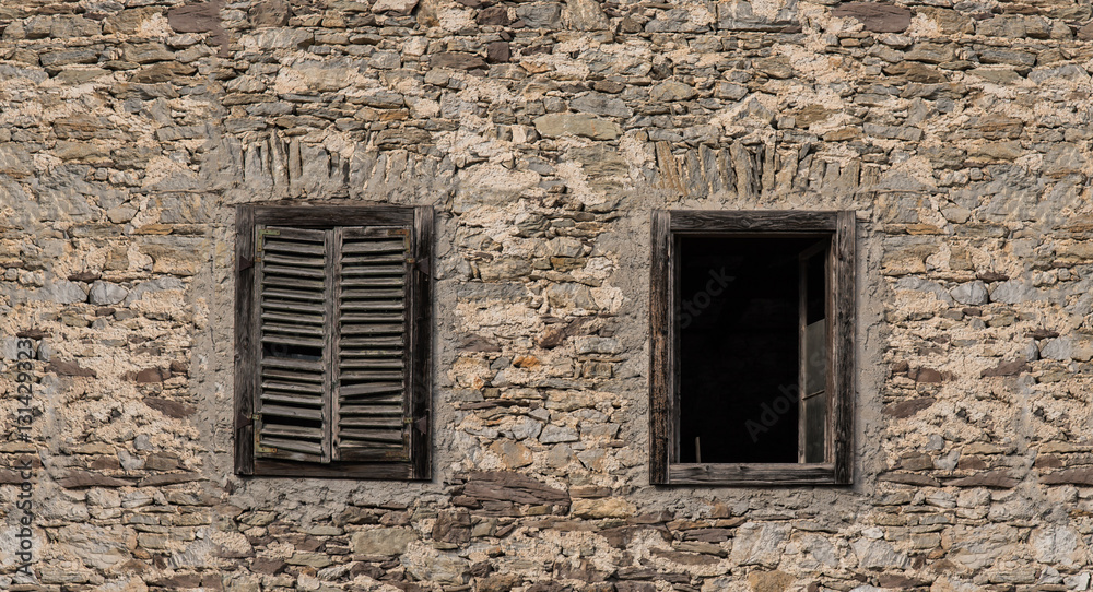 Old building in Northern Italy broken down and worn with windows and old stone facade