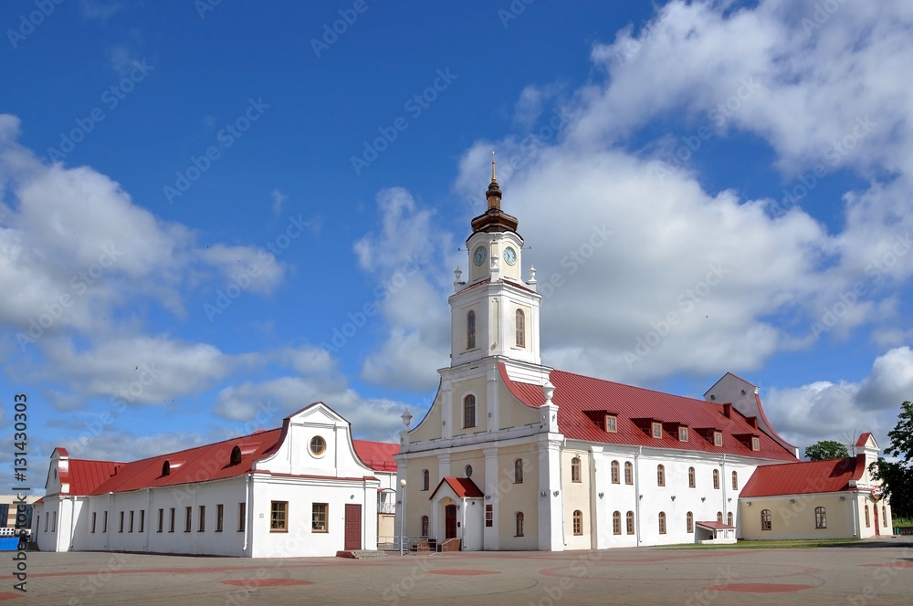 Old Town Hall in Orsha, Belarus. The white building with a tower in the Baroque style with a red roof against the blue sky with clouds.
