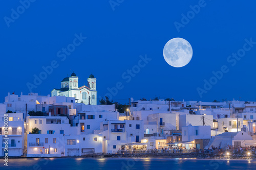Local church of Naoussa village at Paros island in Greece against the full moon.
