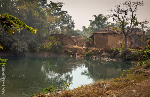 A village pond with ducks surrounded with mud houses. Rural beauty of an Indian village in Bankura, West Bengal.