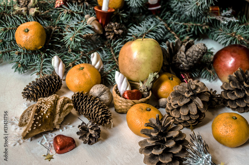 Coniferous branch with fruit  pastries  cones and nuts on light table  