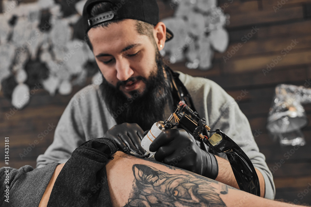 Φωτογραφία Tattoo master in black gloves, tattoo on the skin of black ink tattoo of his client in the salon