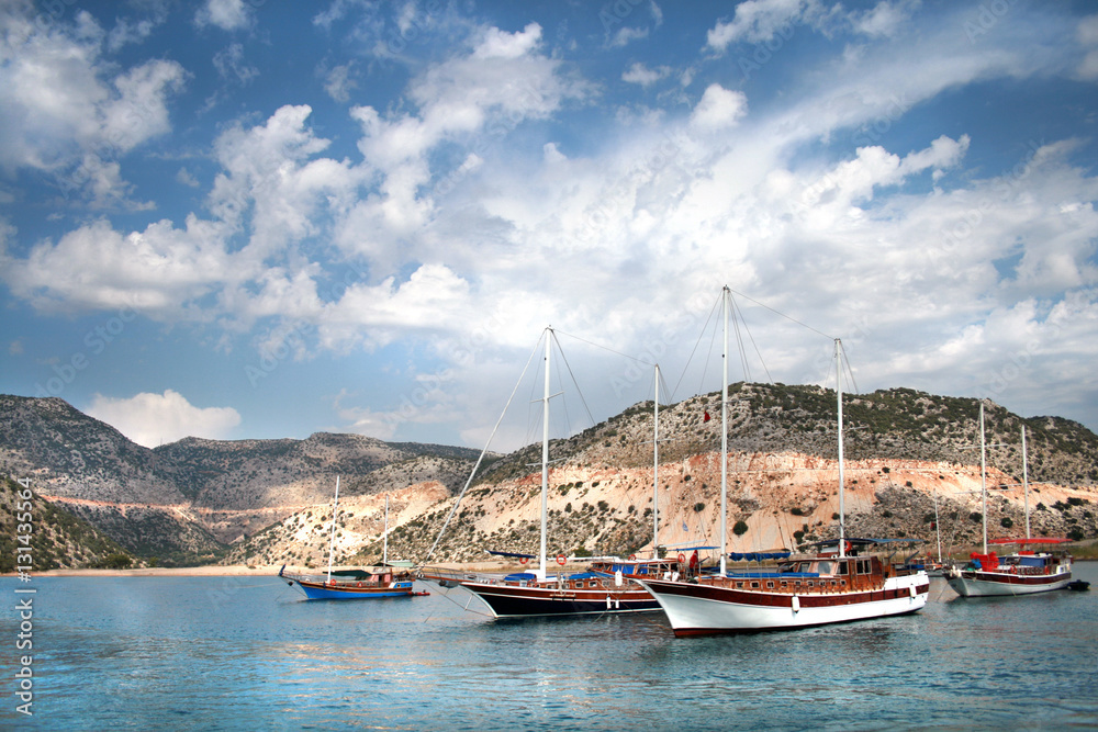 Яхты на фоне острова и облачного неба в Турции