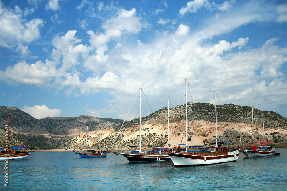 Яхты на фоне острова и облачного неба в Турции