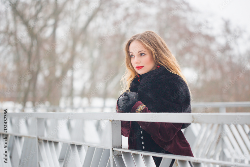 beautiful girl standing on the pedestrian bridge in winter