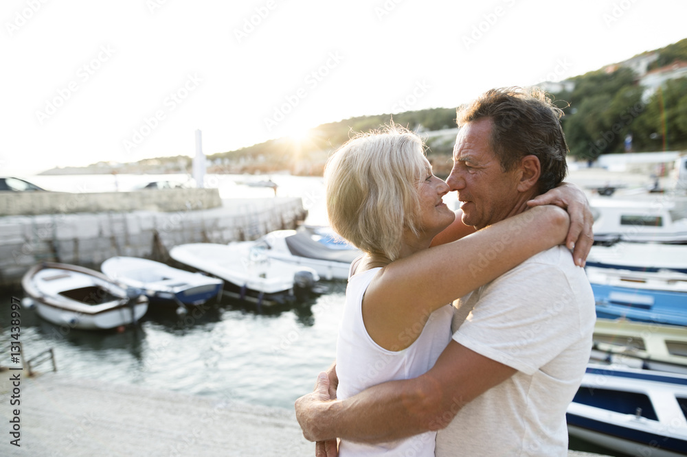 Happy senior couple on quay hugging at evening twilight Happy senior couple on quay hugging at evening twilight