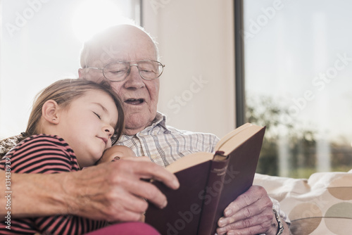 Grandfather reading out story for his granddaughter photo