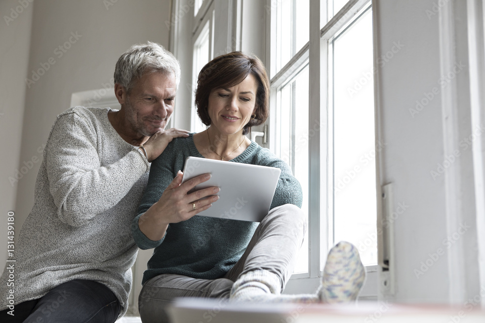 Couple sharing tablet at the window Couple sharing tablet at the window