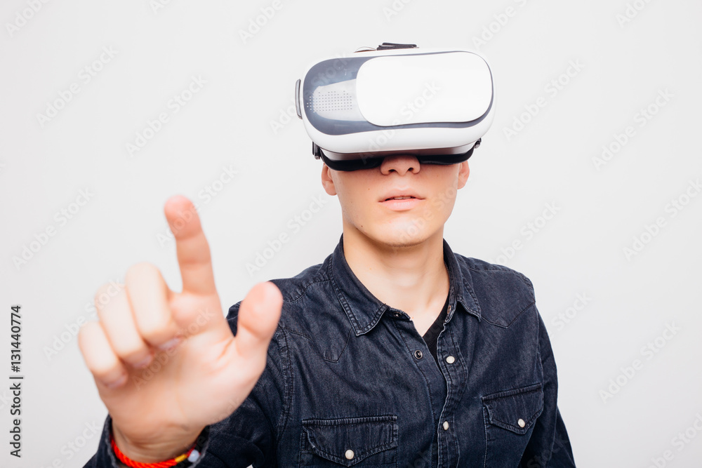 Young man experiencing virtual reality through a VR headset pointed with hands isolated on white background Young man experiencing virtual reality through a VR headset pointed with hands isolated on white background
