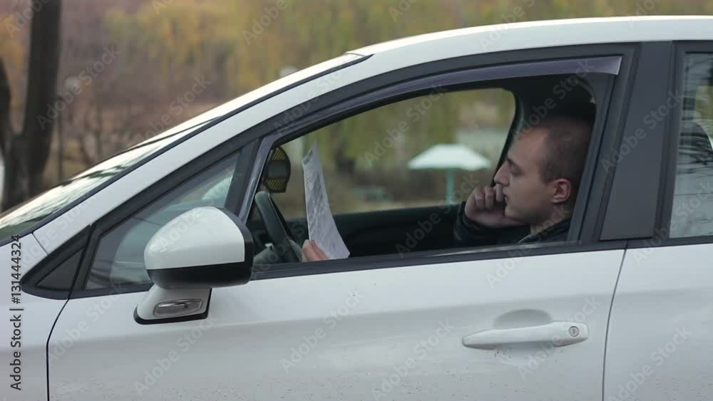 Young man speaking by phone in the car.