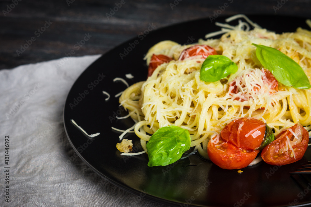 Pasta with tomatoes and basil on the dark background. Shallow depth of field. Pasta with tomatoes and basil on the dark background. Shallow depth of field.