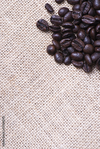 From above shot of coffee beans on tablecloth on wooden table. Vertical shot. Texture.