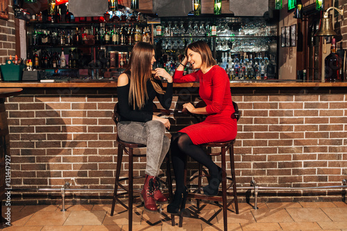 two women sitting at the bar,have fun smile