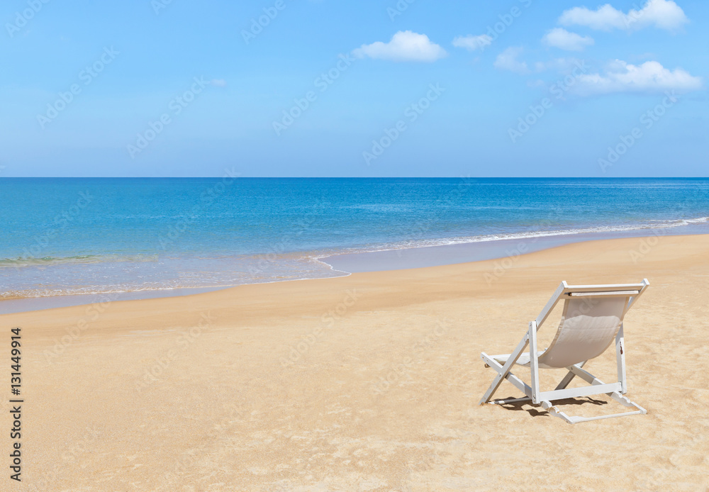 Empty white wooden beach chair on tropical beach with blue sky