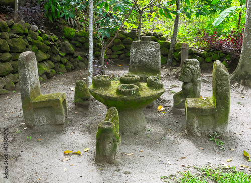 Ancient Indonesian sculptures of backchairs and table carved from stone, at Ambarita Stone Chairs worship, Lake Toba, Samosir, Indonesia photo
