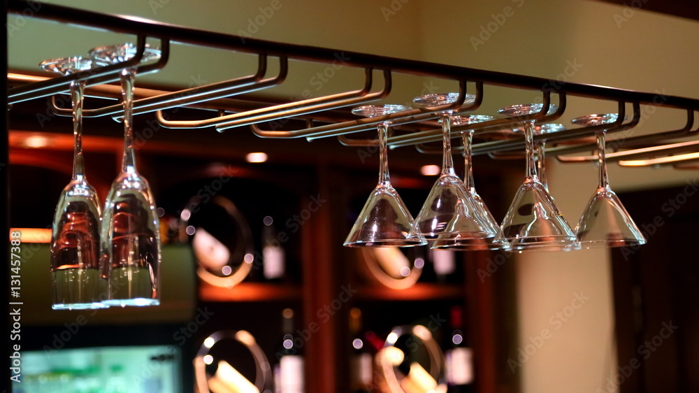 Empty clean wine glasses are hanging above the bar